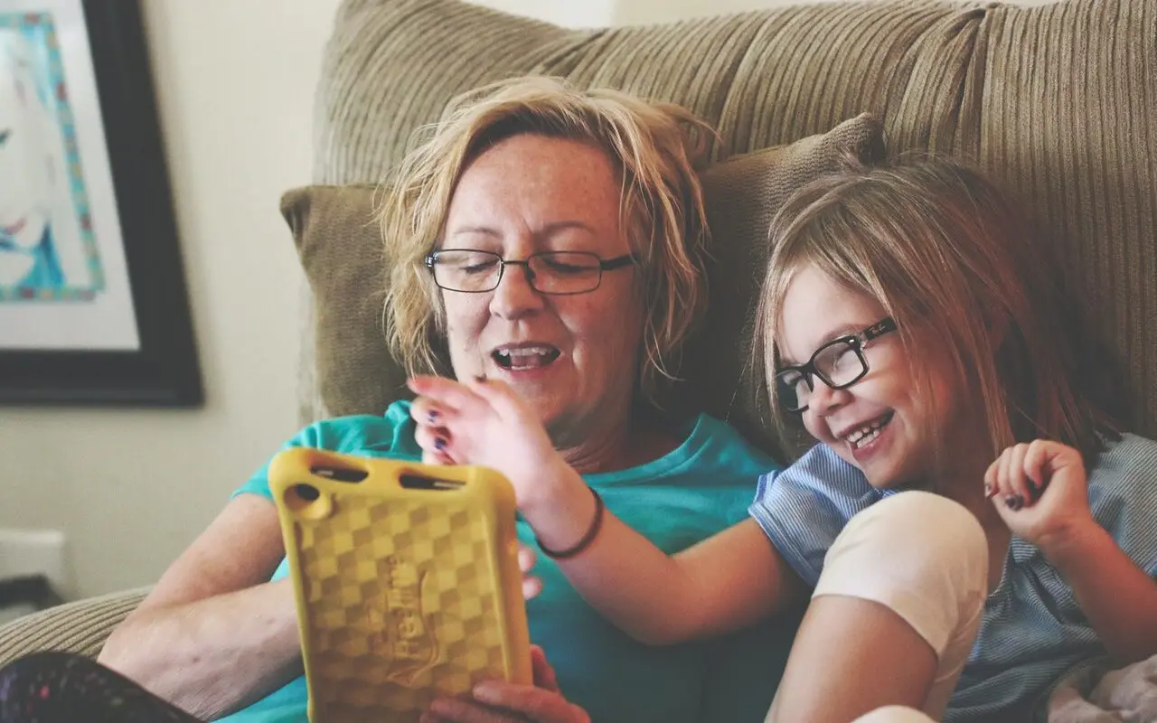 une mère et sa fille sourient en utilisant une application éducative sur tablette