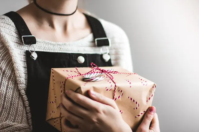 personne offrant un cadeau emballé kraft avec ruban rouge pour enfant