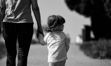 enfant marchant main dans la main avec un adulte en noir et blanc