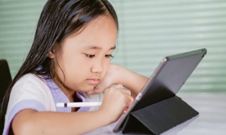 A young girl using a tablet for online learning, focused and engaged with her digital pen.