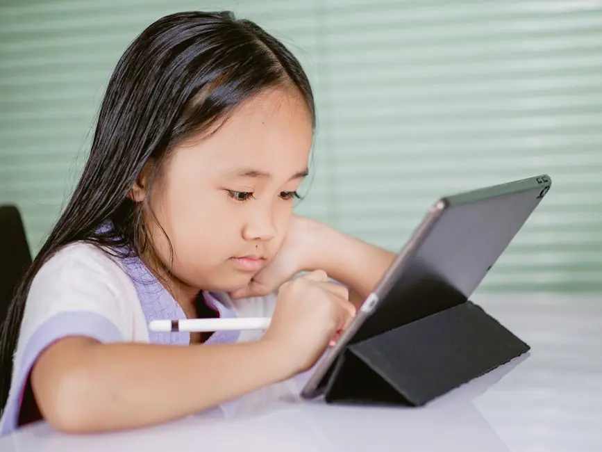 A young girl using a tablet for online learning, focused and engaged with her digital pen.